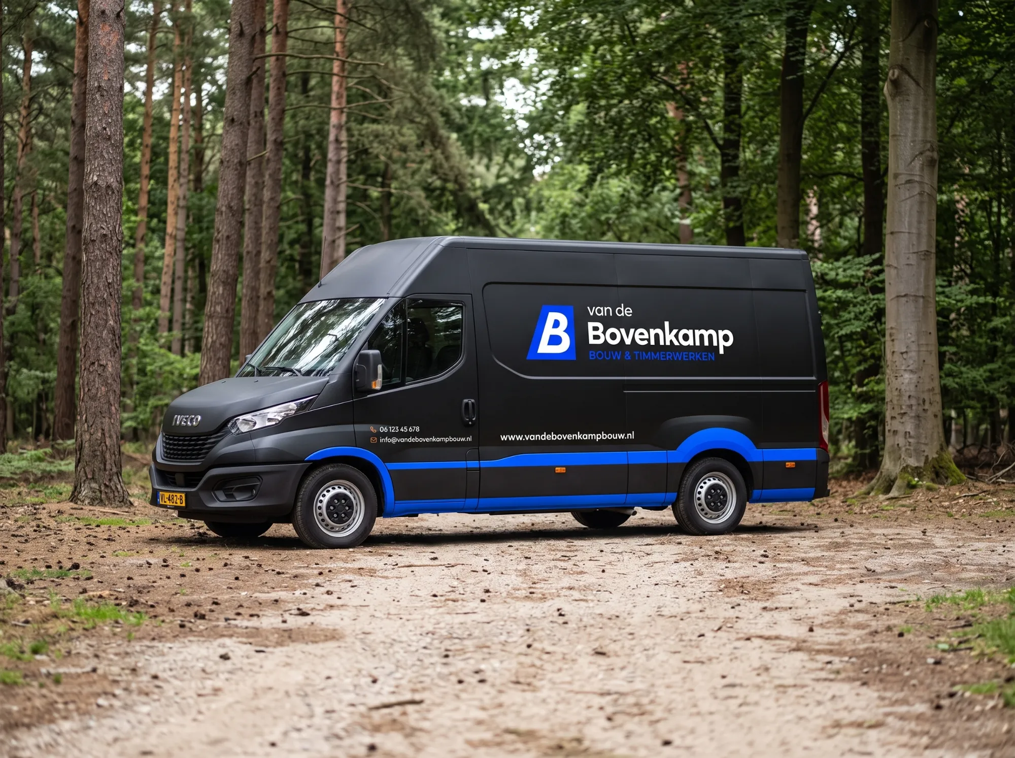 Zwarte Van de Bovenkamp bedrijfsbus op een zandpad in het bos